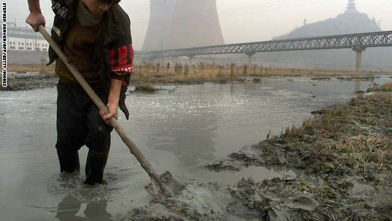 A young migrant worker shovels heavily polluted mu