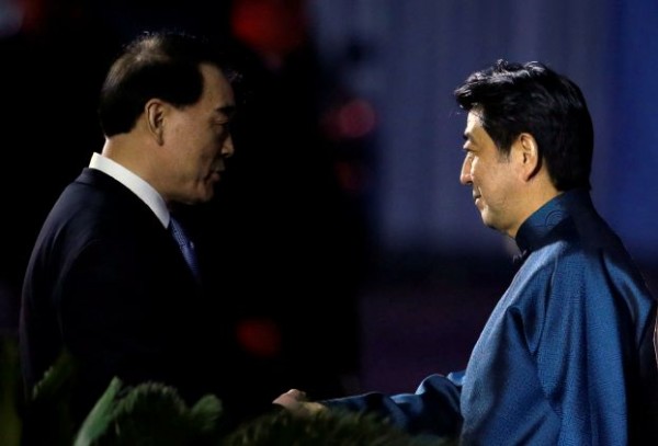 Japanese Prime Minister Shinzo Abe in traditional Chinese-style outfit, shakes hands with China's Vice Foreign Minister Li Baodong as he arrives at Beijing National Aquatics Center, or the Water Cube, for the APEC Welcome Banquet, in Beijing